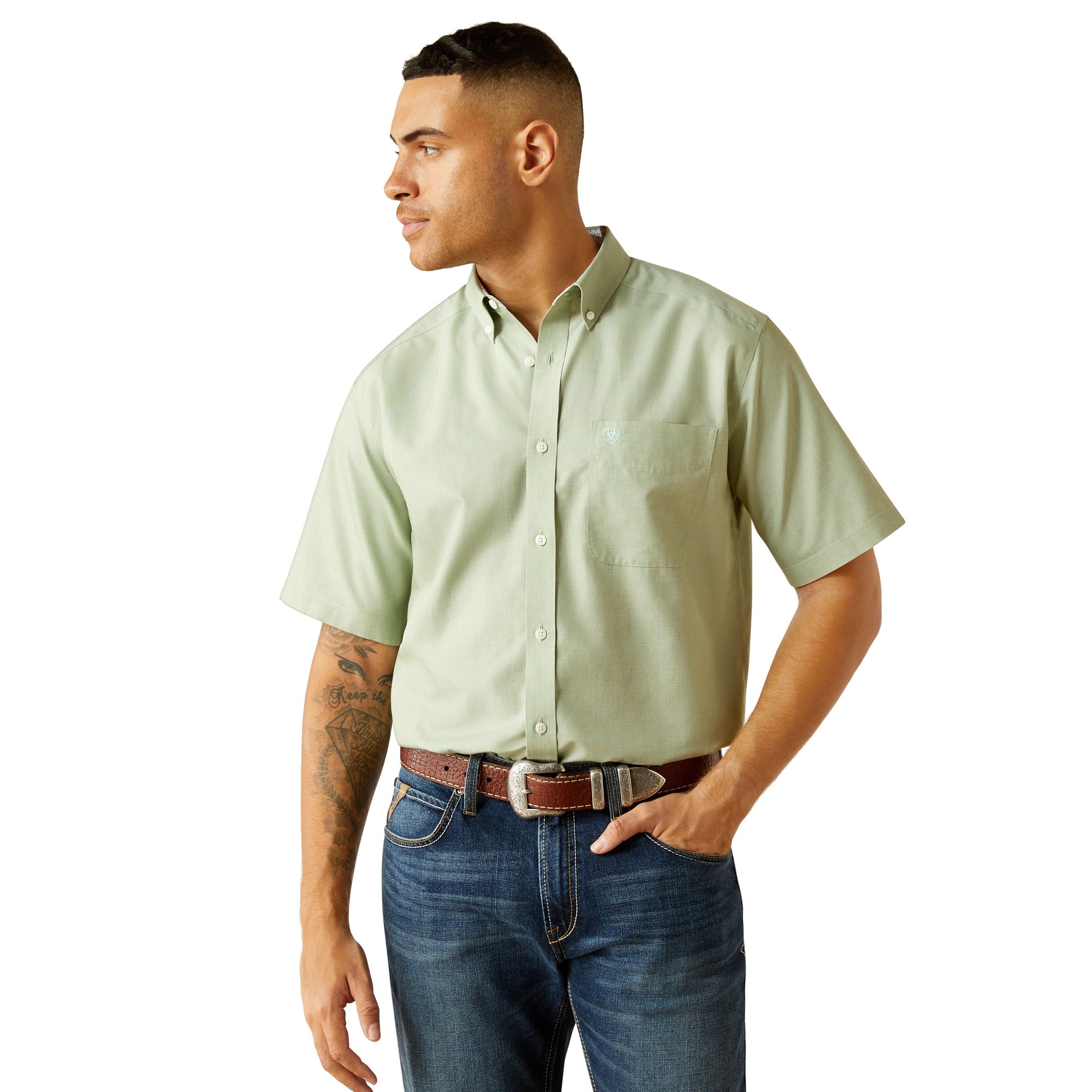 Man wearing a light green short-sleeve shirt and blue jeans on a white background
