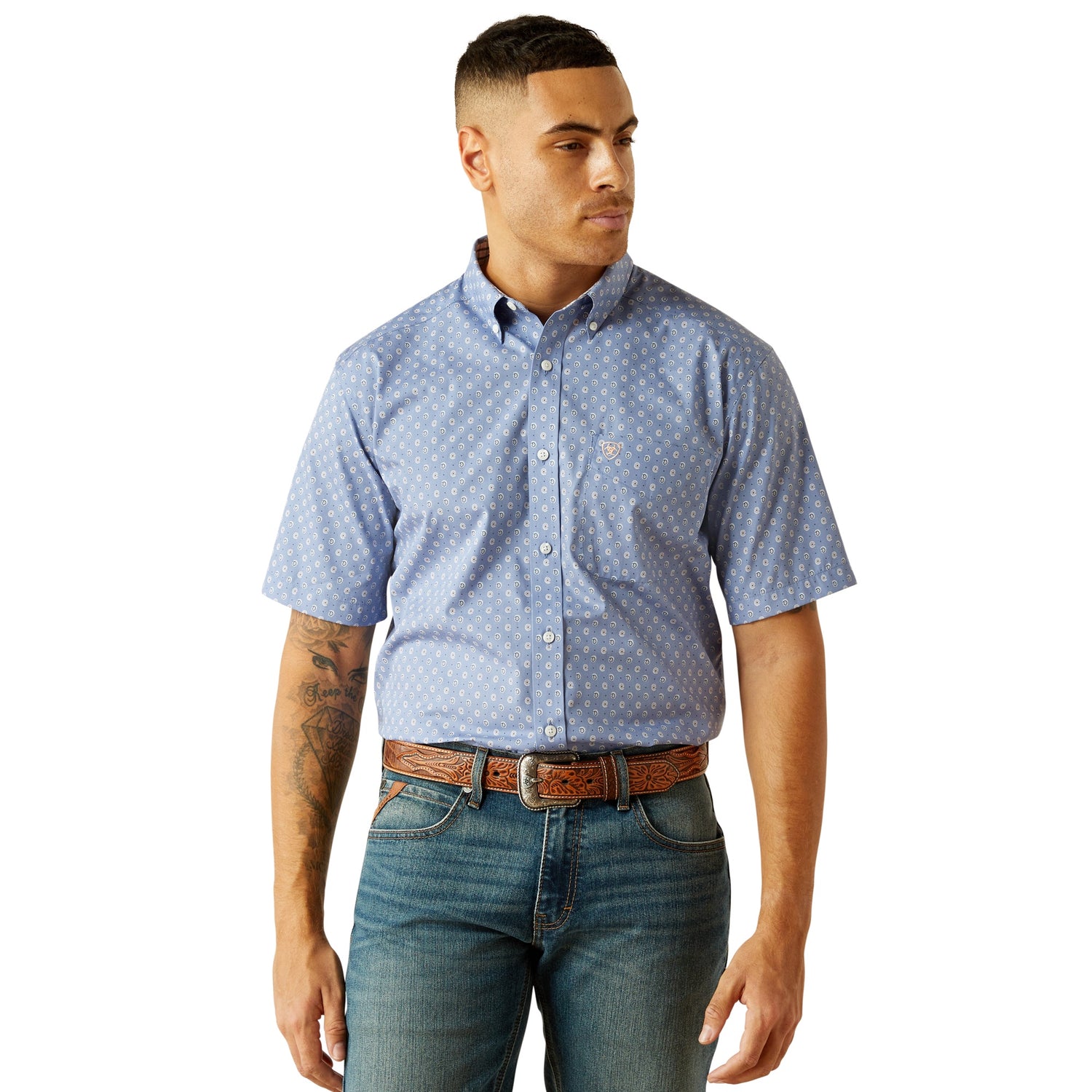 Man wearing a blue patterned short-sleeve shirt and jeans on a white background