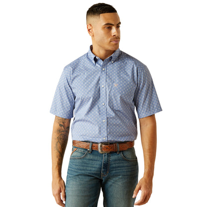 Man wearing a blue patterned short-sleeve shirt and jeans on a white background
