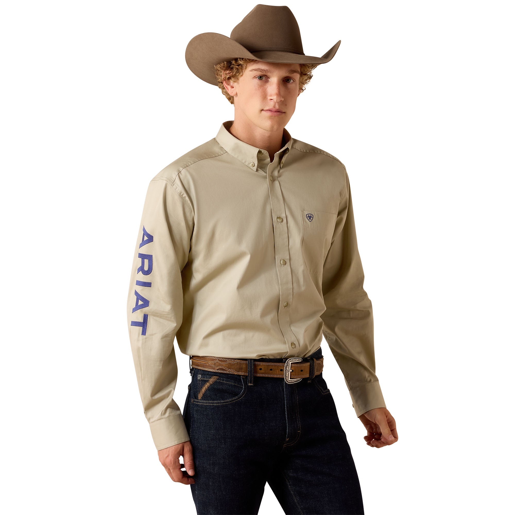 Man wearing a beige Ariat shirt, dark jeans, and a brown cowboy hat on a white background